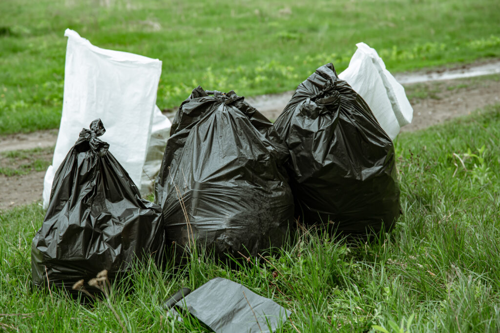 Close-up of garbage bags in the forest on the grass.
